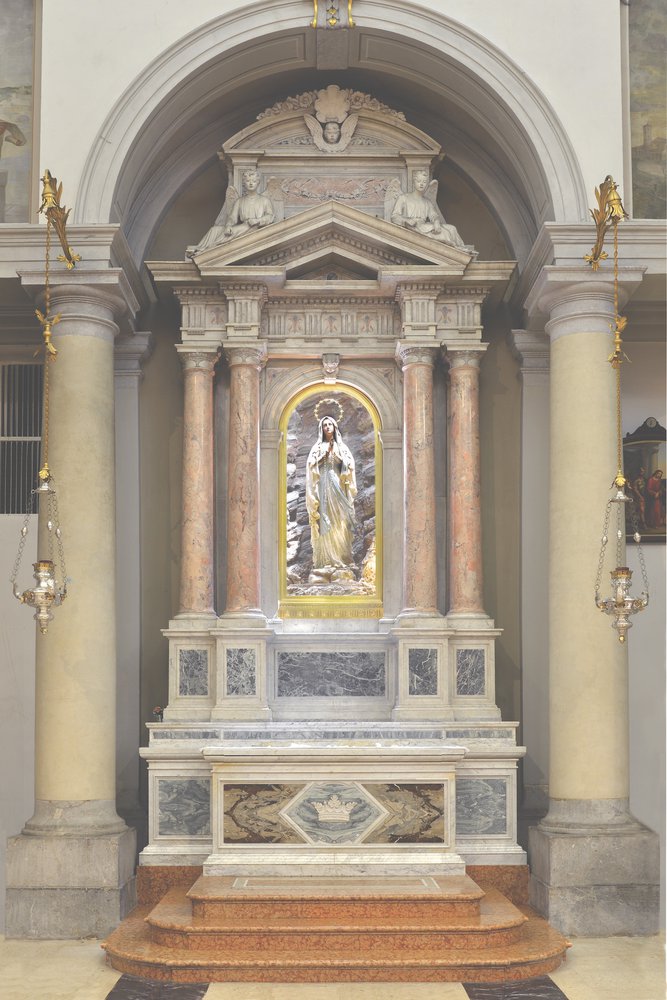 E.D’Aronco, Altare della Beata Vergine Immacolata, 1903, pietra artificiale.  La statua raffigurante la Madonna di Lourdes (1909) è opera di Ferdinando Demetz.
